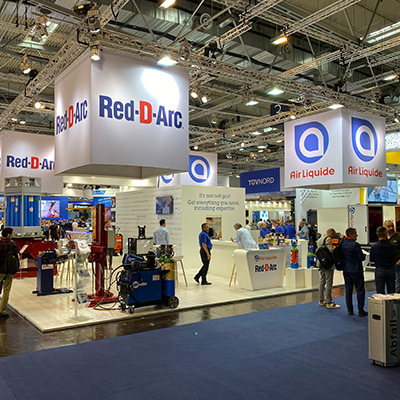 A busy tradeshow floor with selection of welding equipment on display