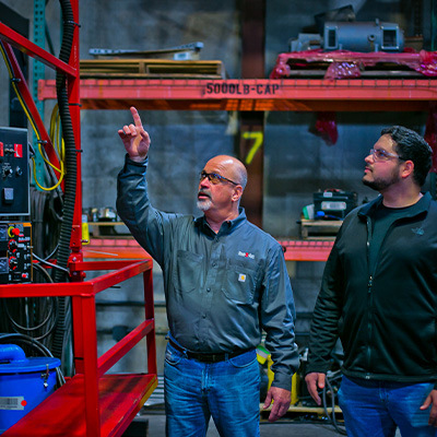 Employee showing customer weld automation equipment on display in warehouse