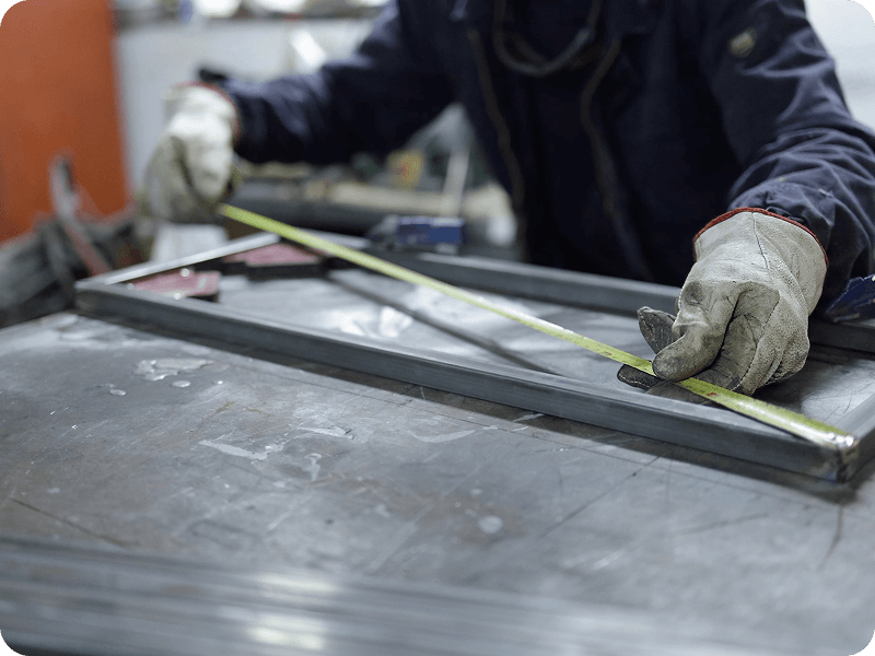 a person in a workshop measuring a rectangular piece of metal from corner to corner
