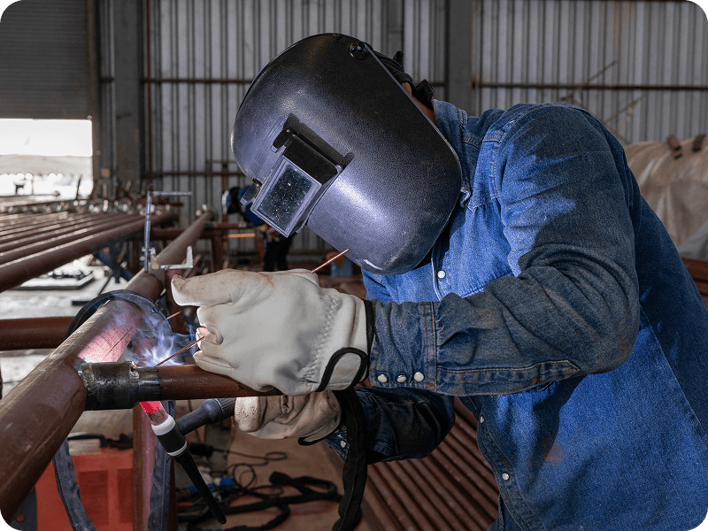 a person on a ladder welding a copper pipe
