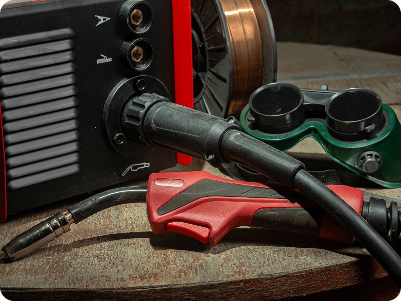 a closeup of a welding machine and a pair of safety goggles on a table