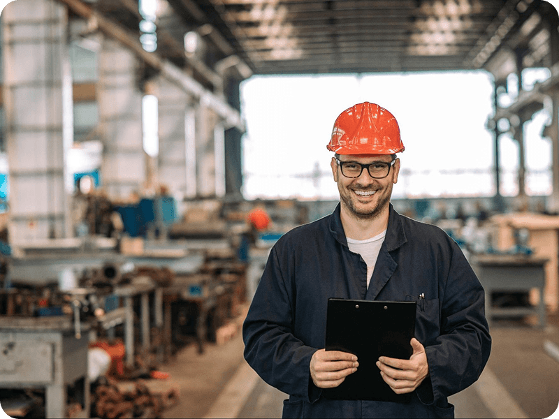 a man in an orange hardhat smiling with a clipboard