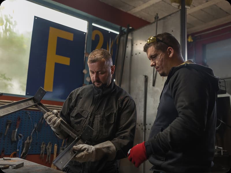 two men inspecting a piece of metal after welding