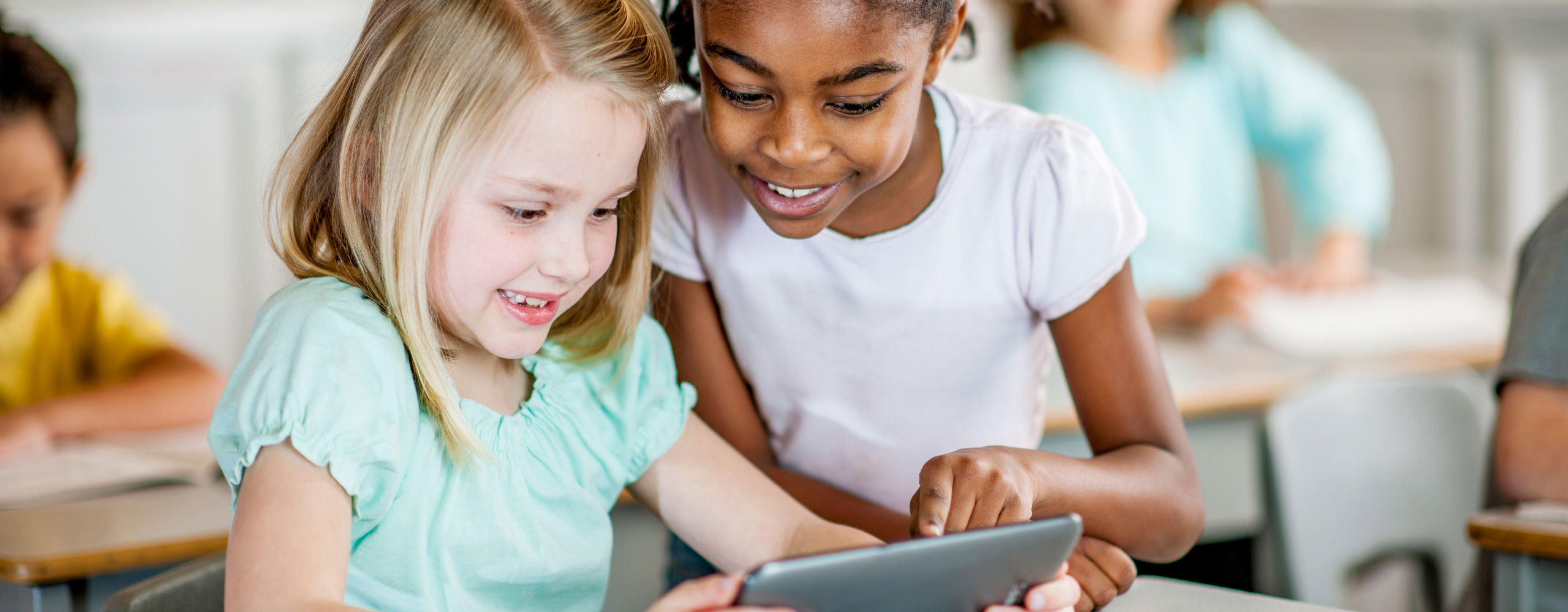 Female elementary students looking at tablet together