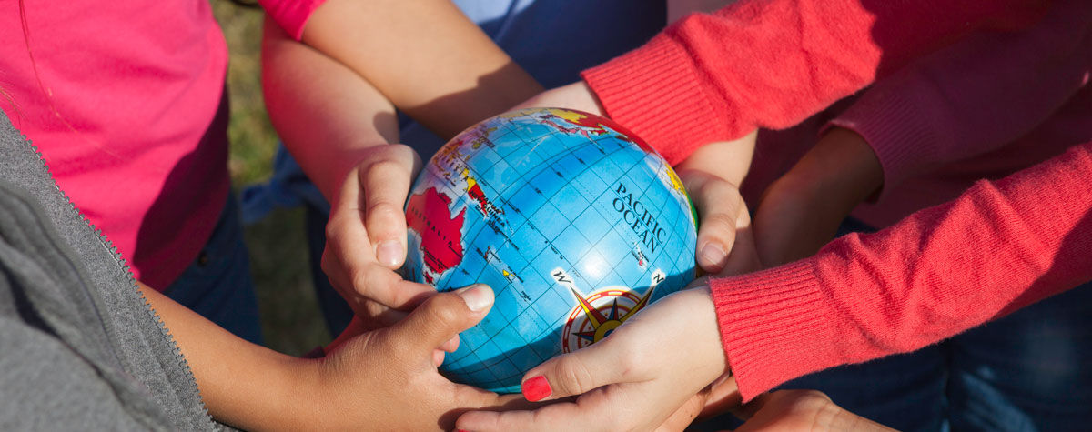 children's hands connecting around a globe