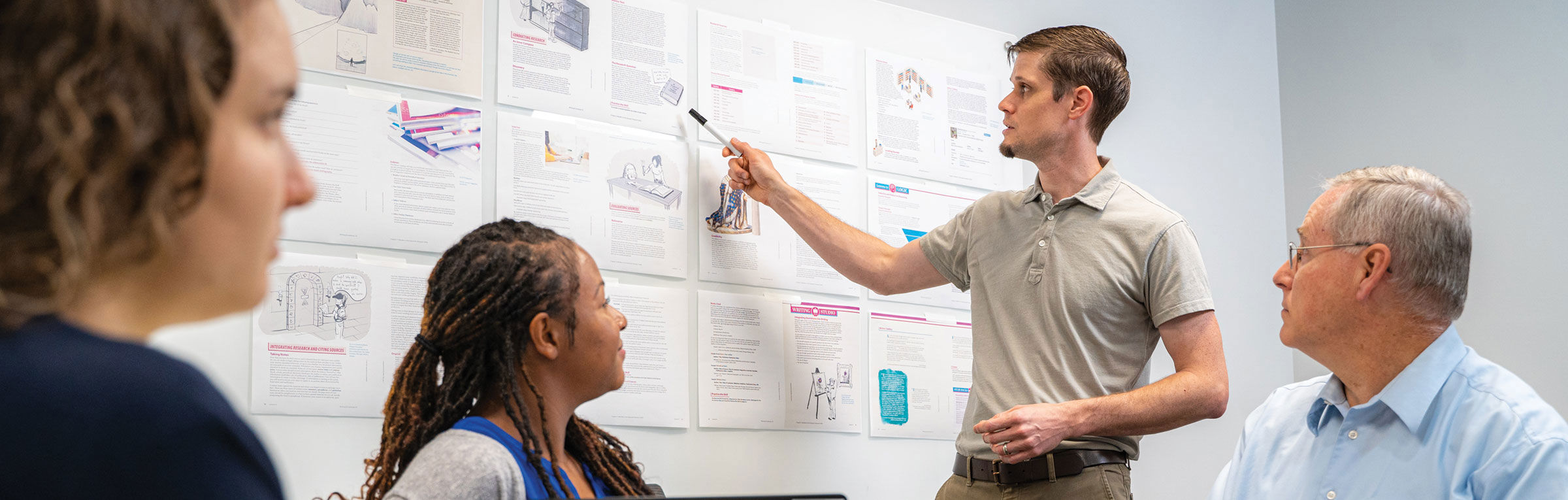 people reviewing a whiteboard with textbook pages displayed